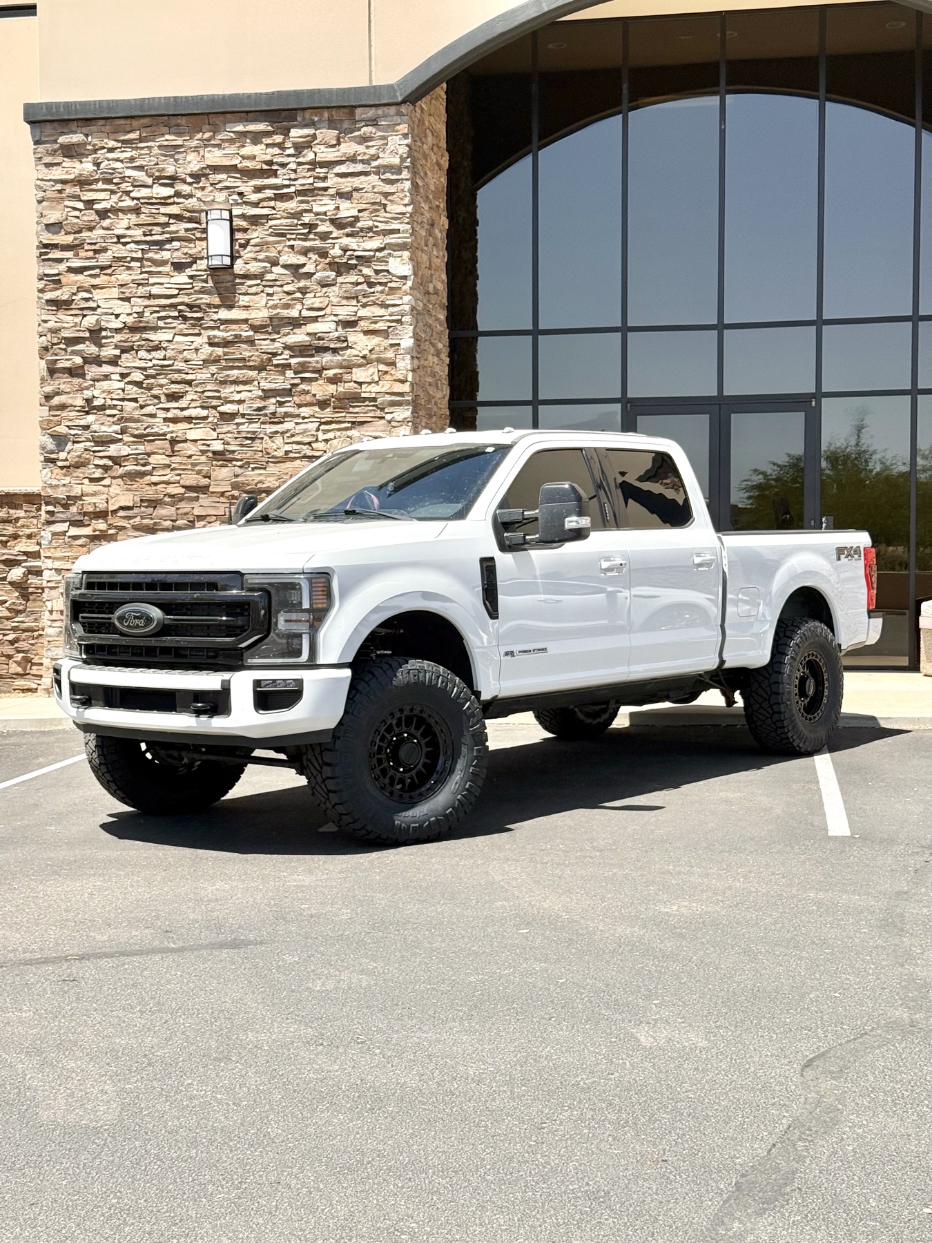 White Ford F-250 with blacked-out trim and grille in front of a storefront