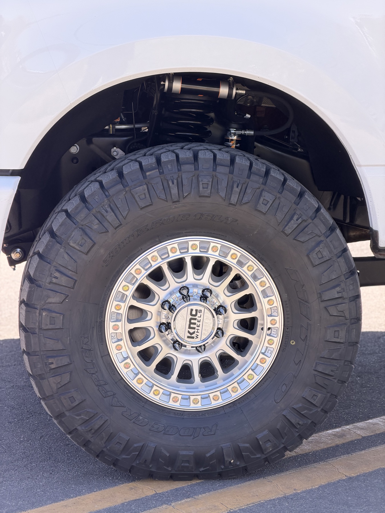 KMC beadlock wheel with 38-inch Nitto Ridge Grappler tire and coilover on a lifted truck