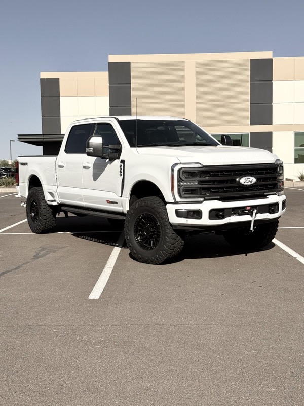 White Ford F-250 Super Duty on a lift kit outside the shop