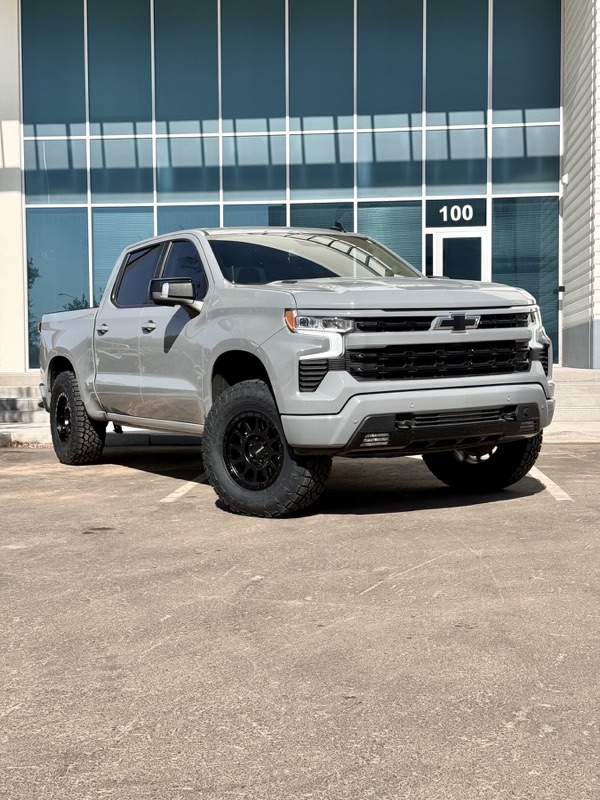 Gray Chevy Silverado RST lifted at a glass building