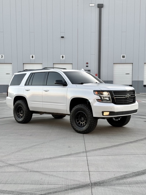 White Chevy Tahoe lifted at the shop bay doors